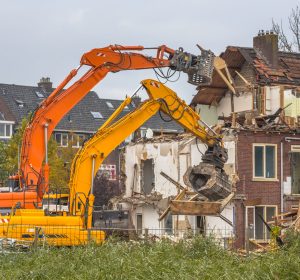 Two Demolition cranes demolishing old row of houses in the Netherlands